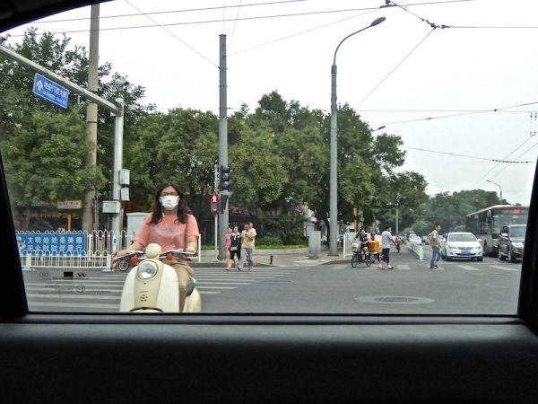 Chinois en scooter portent un masque, à Pékin en Chine