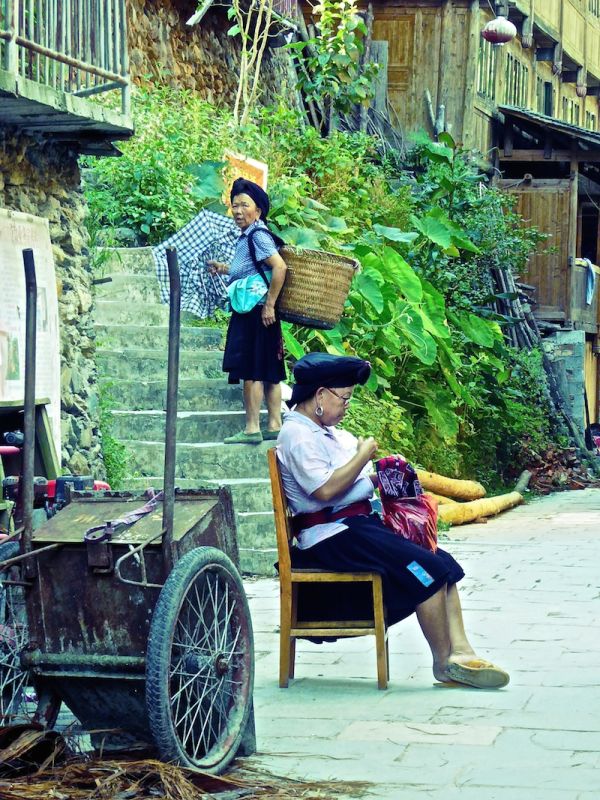 Une vieille dame porte sur son dos les bagages des touristes, dans les rizières de Longji