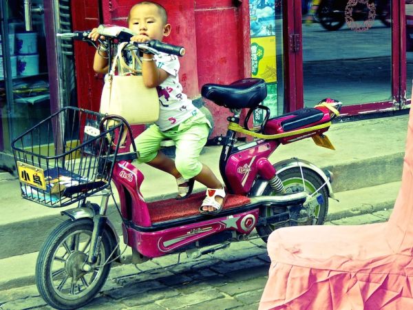 Scène de rue dans la vieille ville de Pingyao : un enfant sur son scooter